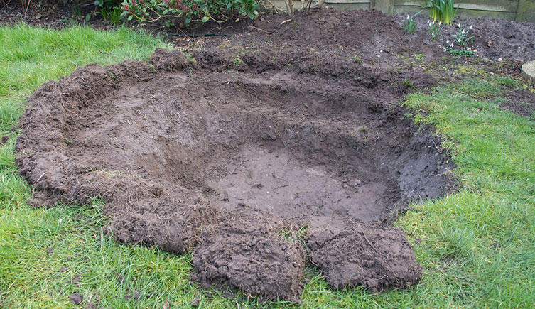 An area of lawn where a pond is being dug out