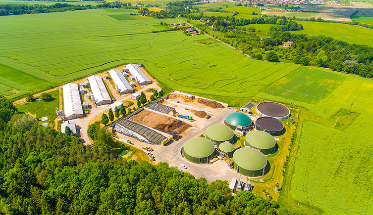 Several large round storage containers on a site with buildings and lorries