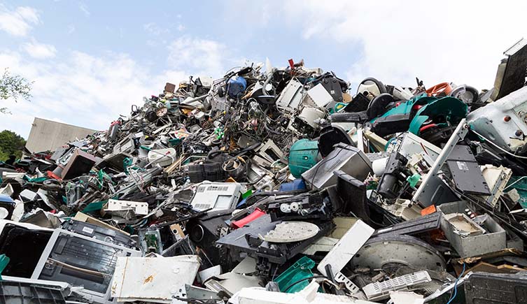 A mound of discarded electronics below a blue sky.