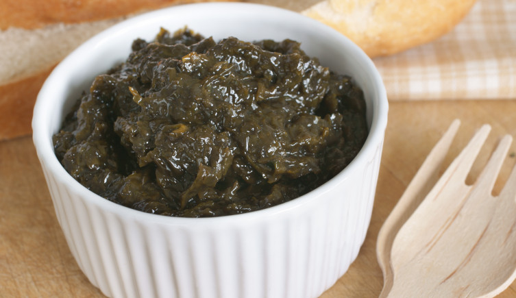 A pot of the chutney-like laverbread next to two wooden forks.