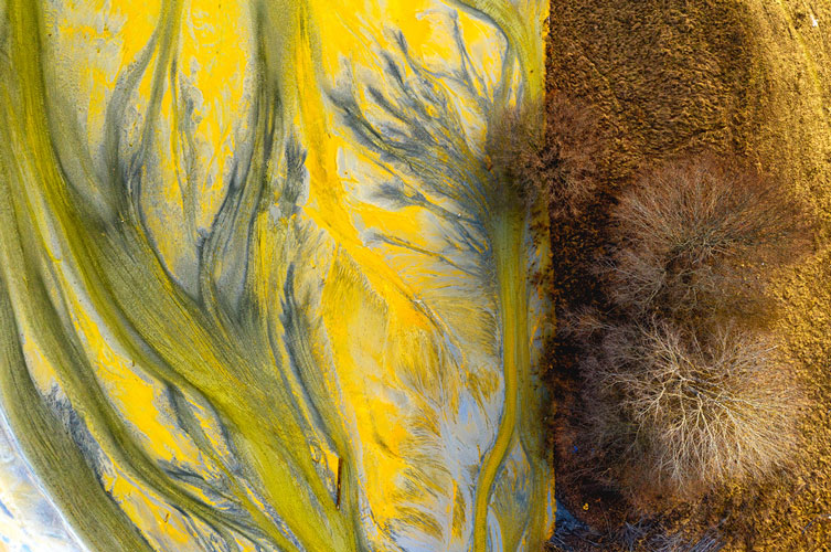 The autumn-coloured land meets the yellow poisoned lake