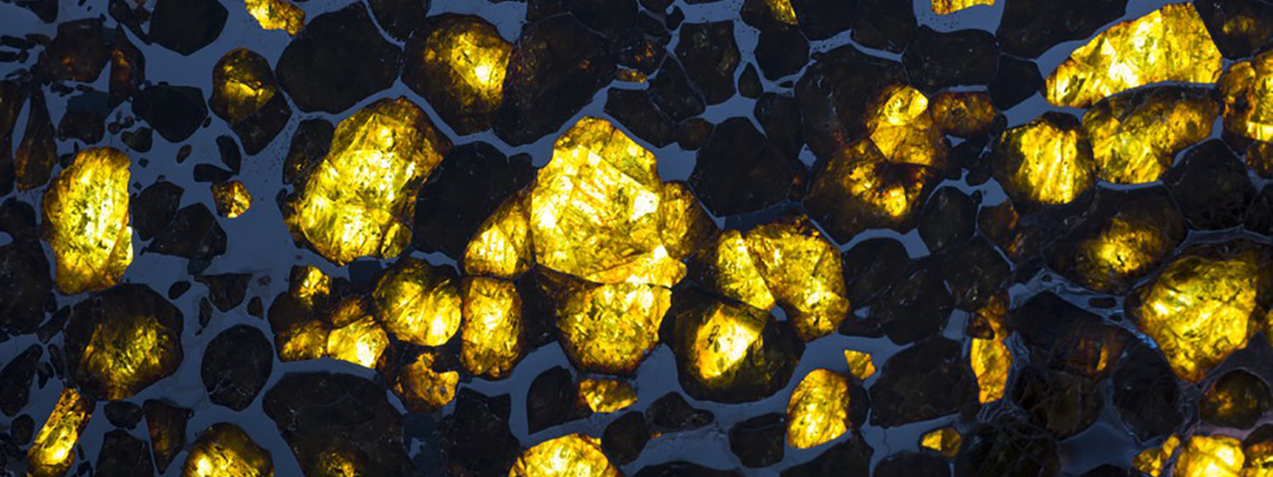 A close up of a meteorite with areas of light shining through yellow rock