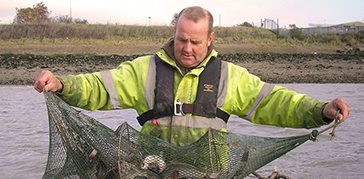 A man holding a net by the water 