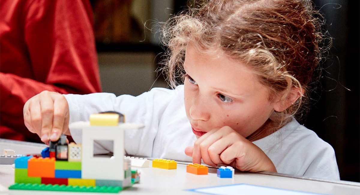a child concentrating as she builds with lego bricks