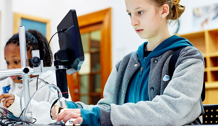 a girl using a computer mounted microscope to examine a specimen