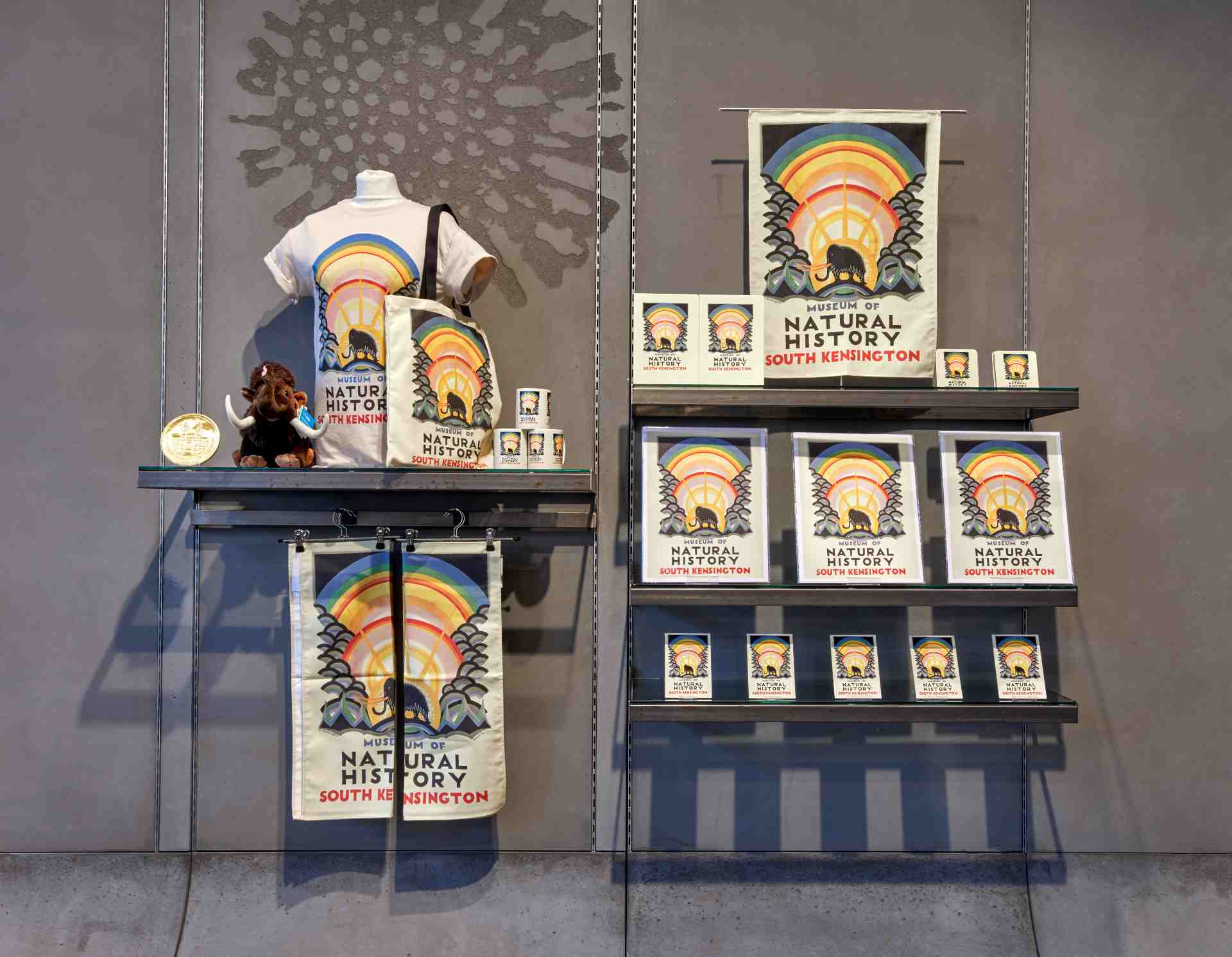 Souvenirs like t-shirts, books and posters with art from the Museum are seen with the grey background of a wall 