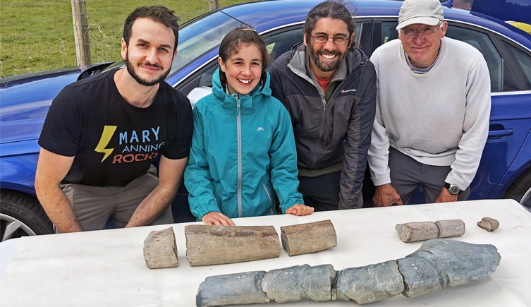 Dr Dean Lomax, Ruby Reynolds, Justin Reynolds and Paul de la Salle standing behind a table with the fossil jawbones