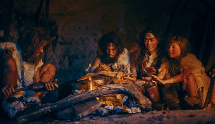 Una foto de modelos vestidas como los primeros Homo sapiens alrededor de un fuego