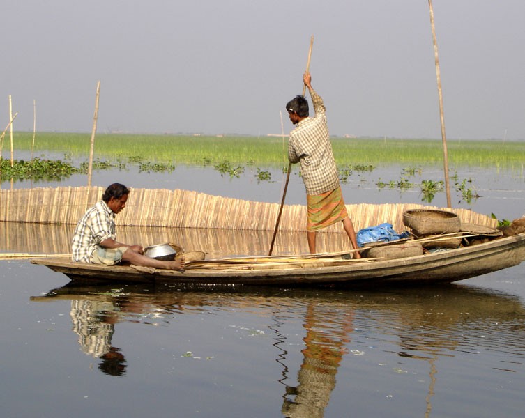A man rows a boat standing up, while another sits