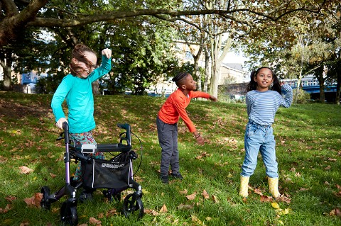 Three children in a park race and make shapes with their bodies 
