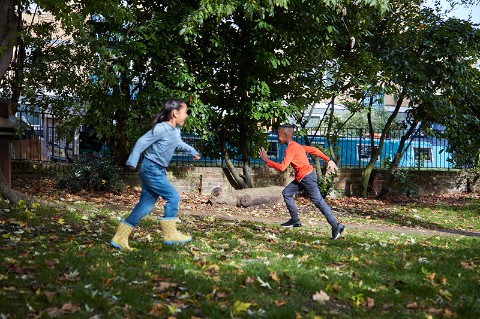 two children run through a green park in summer in opposite directions