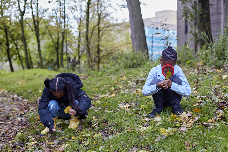 two children crouch down and look at the ground