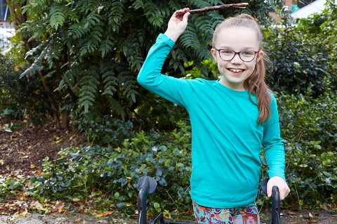 A child holds a stick above her head