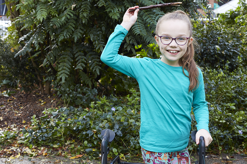 A child holds a stick above her head
