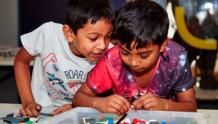 Two boys playing with Lego in a plastic box